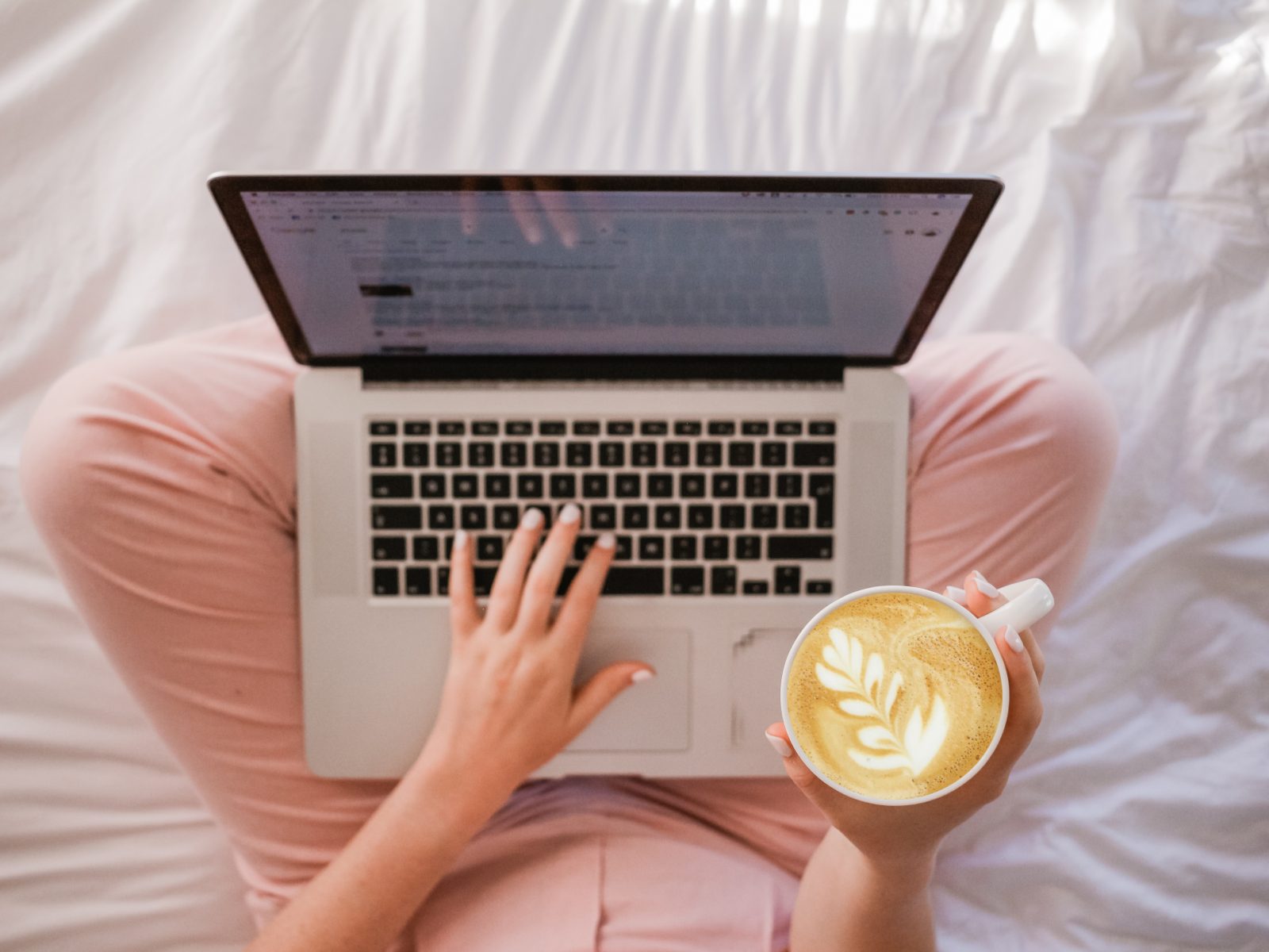 Woman enjoying cappuccino while on the MacBook Pro