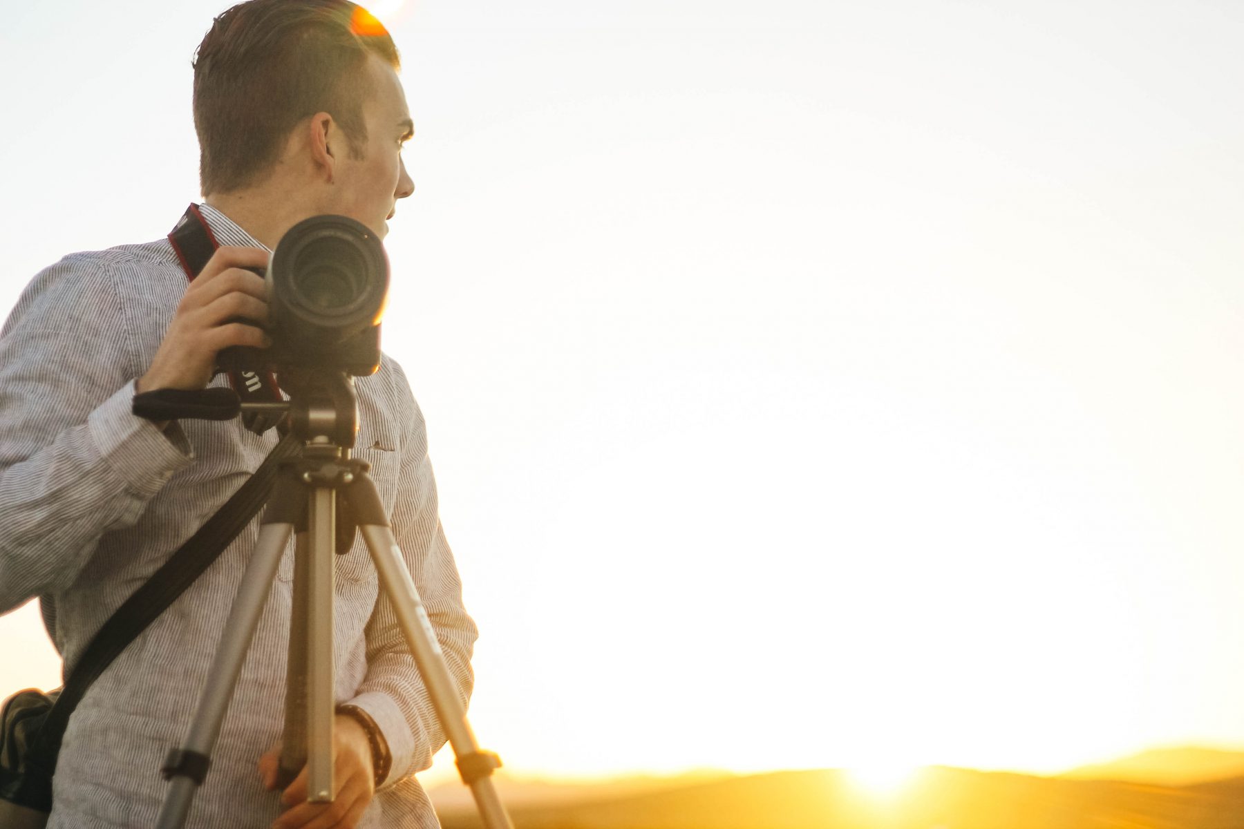 Photographer standing next to a tripod with camera attached