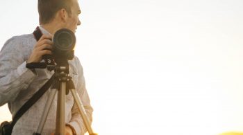 Photographer standing next to a tripod with camera attached