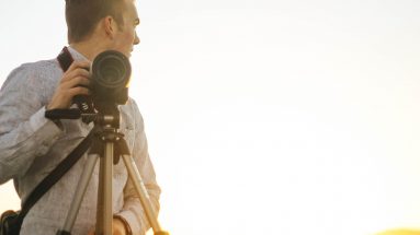 Photographer standing next to a tripod with camera attached