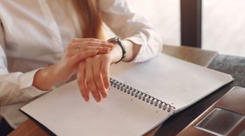 Maximize Your Productivity and Profitability with Effective Time Management Strategies—photograph of a female business person looking at her watch and a daily planner.
