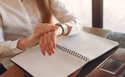 Maximize Your Productivity and Profitability with Effective Time Management Strategies—photograph of a female business person looking at her watch and a daily planner.