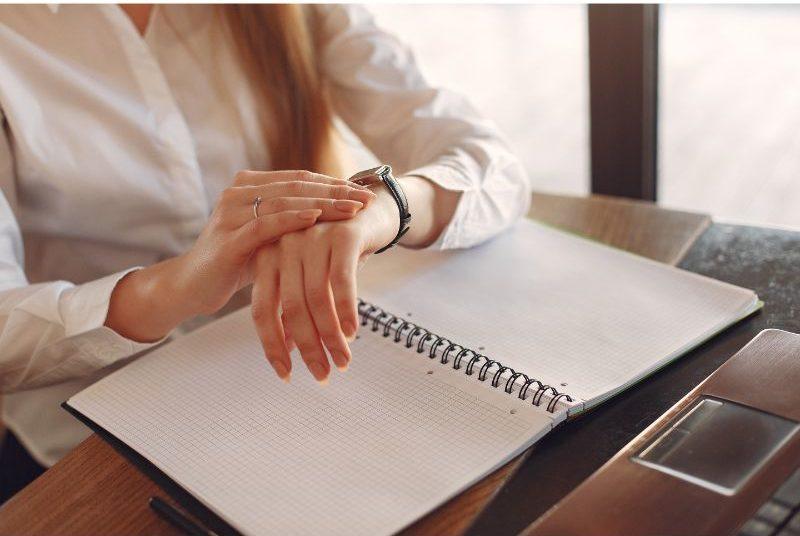 Maximize Your Productivity and Profitability with Effective Time Management Strategies—photograph of a female business person looking at her watch and a daily planner.