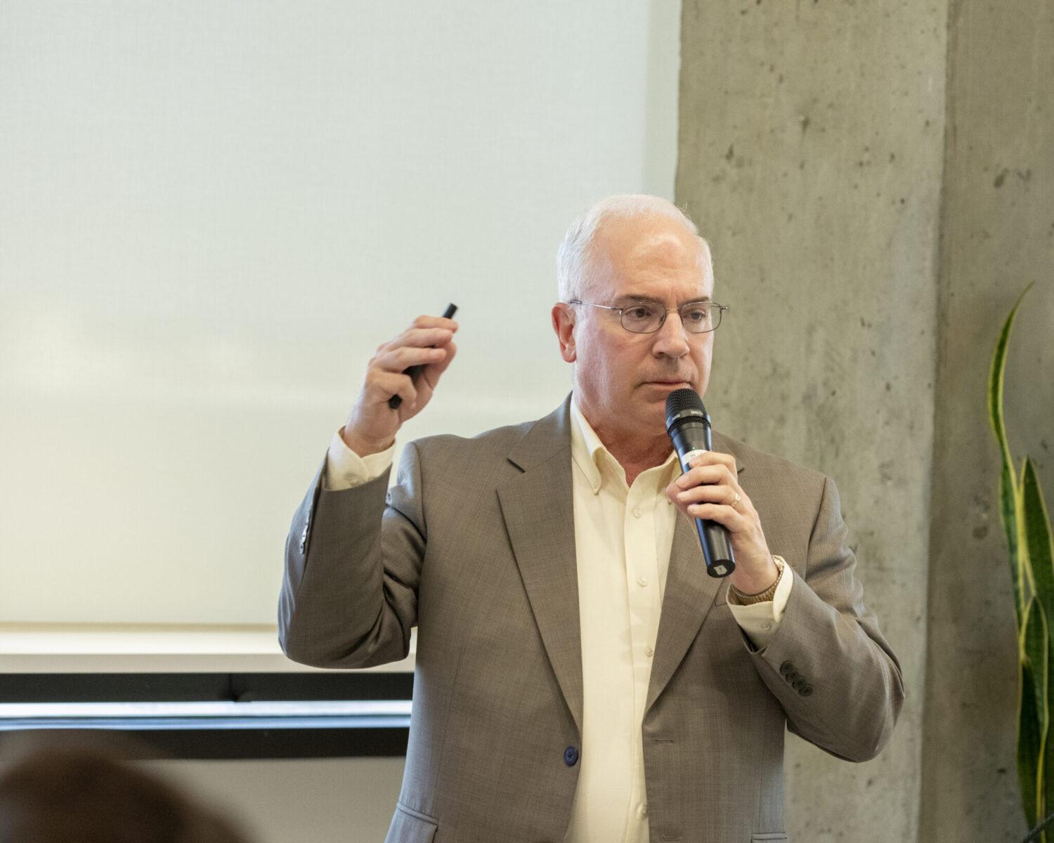 Speaker holding a microphone talking to his audience.