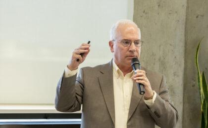 Speaker holding a microphone talking to his audience.