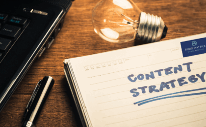 The notebook with the words Content Strategy is written in blue ink. The notebook is next to a light bulb and a laptop computer. If you are having challenges with your content marketing, you need to rethink your strategy.