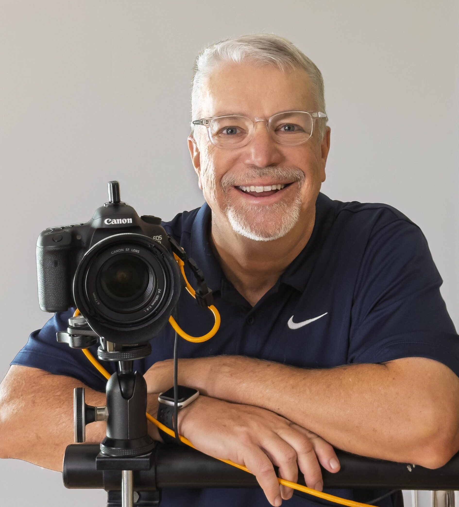 Business Coaching for Photographers is represented by Doug smiling next to his camera